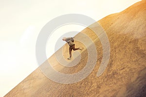 Brave man with backpack running on a dune