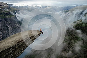 Brave man sitting on the edge Trolltunga. Norway