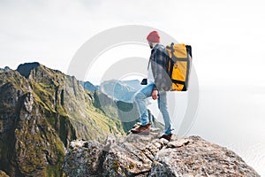 Brave man tourist with backpack standing on the edge mountain above sea and looking forward away photo