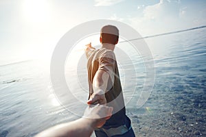 Brave man guiding traveling woman through the water in ocean photo