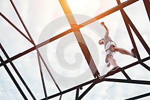 Brave and risky man balancing on the top of high metal bridge