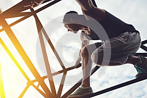 Brave and risky man sitting on the top of high metal bridge