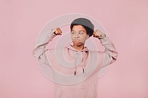 Brave student girl in hoodie posing on pink backdrop