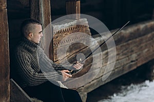 Brave warrior holding sword near historical wood castle building