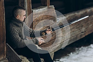 Brave warrior holding sword near historical wood castle building