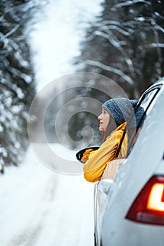 Brave woman drive by car and looking away to winter forest