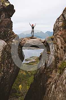 Brave woman traveler standing on hanging stone between rocks