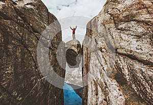 Brave woman traveler standing on Kjeragbolten raised hands photo