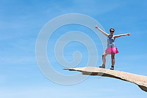 Brave young adult woman hiker stands on top of Potato Chip Rock in San Diego California