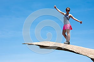 Brave young adult woman hiker stands on top of Potato Chip Rock in San Diego California