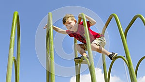 Brave young boy cimbing on playframe.