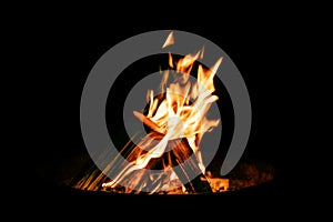 Brazier or fire bowl with burning wood logs in front of black ba photo
