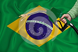 BRAZIL flag Close-up shot on waving background texture with Fuel pump nozzle in hand. The concept of design solutions. 3d