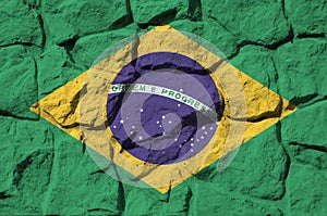 Brazil flag depicted in paint colors on old stone wall closeup. Textured banner on rock wall background photo