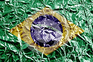 Brazil flag depicted in paint colors on shiny crumpled aluminium foil closeup. Textured banner on rough background photo