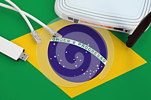 Brazil flag depicted on table with internet rj45 cable, wireless usb wifi adapter and router. Internet connection concept