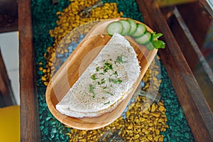 Brazil food tapioca with cucumber peaces on decorative wooden tray and glass table surface south America entourage cafe interior