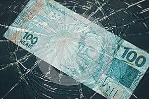 Brazil money, Fall of the Brazilian currency, Weakening of the real 100 Reais banknote lying behind the broken glass, Financial