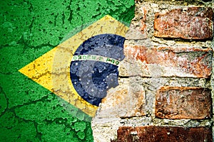 Brazil national flag painted cracked divided peeling pain brick wall cement facade background. Political economical crisis concept