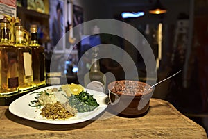 Brazilian beans and pork feijoada, with rice flour salad over piece of wood with blurs