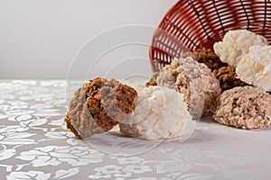 Brazilian cocada coconut candy dropped from a basket on a table with white towel, selective focus