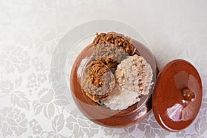 Brazilian cocada coconut candy placed in a ceramic pot on a table with white tablecloth, top view