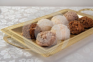 Brazilian cocada coconut candy placed on a golden tray on a table with white towel, selective focus