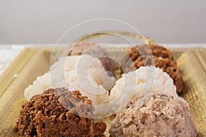 Brazilian cocada coconut candy placed on a golden tray on a table with white towel, selective focus