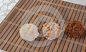 Brazilian cocada coconut candy placed on a wooden mat on a table with white towel, selective focus