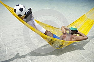 Brazilian Footballer Relaxing with Soccer Balll in Beach Hammock