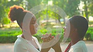 brazilian lesbian couple in white dress spending time together celebrating engagement in summer park outdoor .