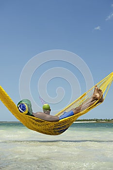 Brazilian Man Relaxing in Beach Hammock with Drinking Coconut