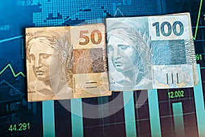 Brazilian money banknotes on a financial chart, banknotes of 100 and 50 Brazilian reai