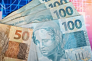 Brazilian money banknotes on a financial chart, banknotes of 100 and 50 Brazilian reai