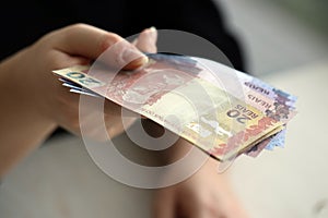 Brazilian money bills in woman hand. Female gives bunch of brazilian reais to us