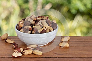 Brazilian nut, known as `Castanha do ParÃÂ¡` in a bowl on a wooden table with an unfocused garden background. photo