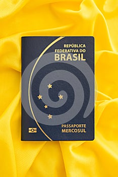 Brazilian passport on yellow fabric representing the Brazilian flag.