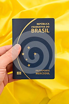 Brazilian passport on yellow fabric representing the Brazilian flag.