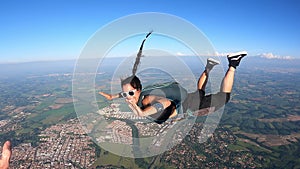 A Brazilian skydiver in free fall, on a summer day. Smiling and confident