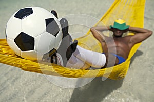 Brazilian Soccer Player Relaxes with Football in Beach Hammock