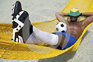 Brazilian Soccer Player Relaxes with Football in Beach Hammock