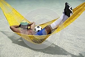 Brazilian Soccer Player Relaxing with Football in Beach Hammock