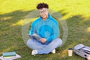 Brazilian student guy browsing internet on digital tablet learning outside