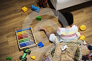 Brazilian toddler girl playing wooden toys on the floor