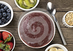 Brazilian typical acai bowl with fruits and muesli over wooden background