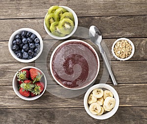 Brazilian typical acai bowl with fruits and muesli over wooden background