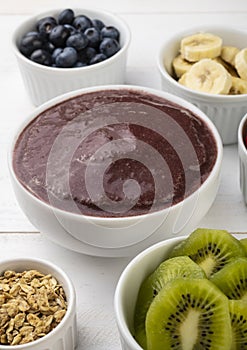 Brazilian typical acai bowl with fruits and muesli over wooden background