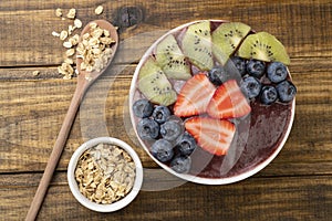 Brazilian typical acai bowl with fruits and muesli over wooden background