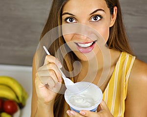 Brazilian woman eating light yogurt at home. Close up from above. Healthy concept