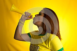 Brazilian woman fan celebrating on football match on yellow back photo